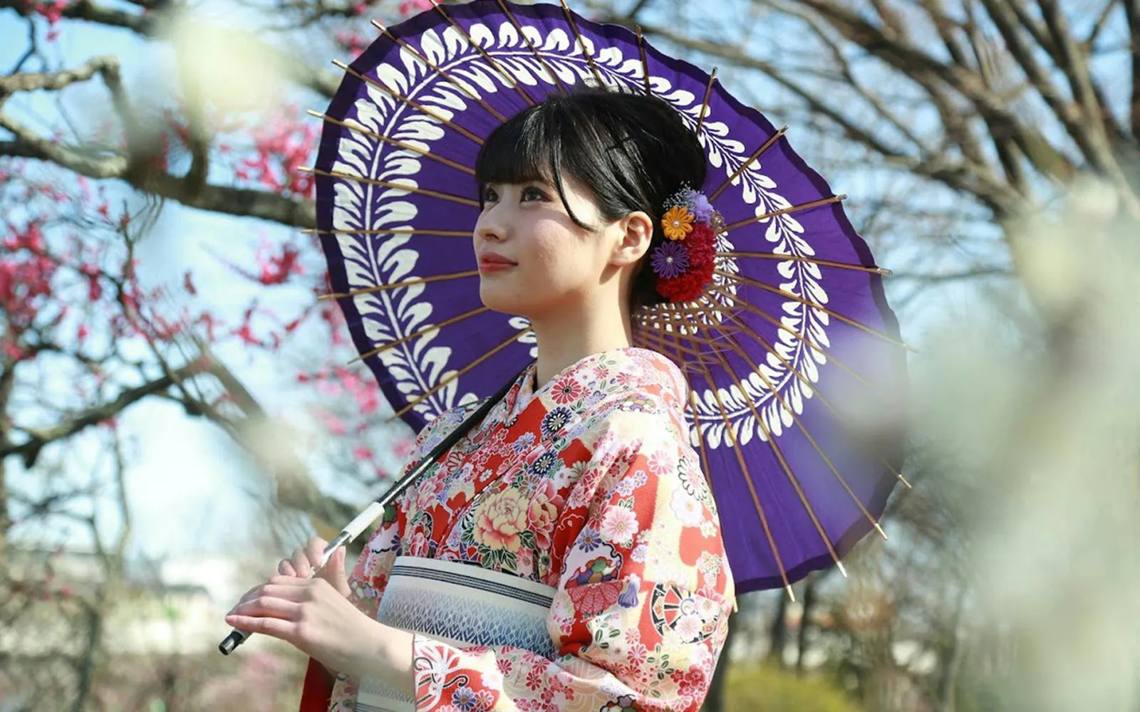 Woman in floral kimono with colorful umbrella at Rental Kimono Okamoto, Japan.