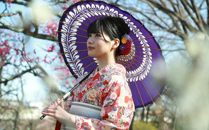 Woman in floral kimono with colorful umbrella at Rental Kimono Okamoto, Japan.