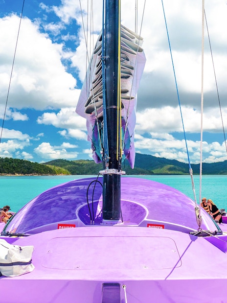 Sailing on a purple catamaran in Airlie Beach with passengers enjoying the view.