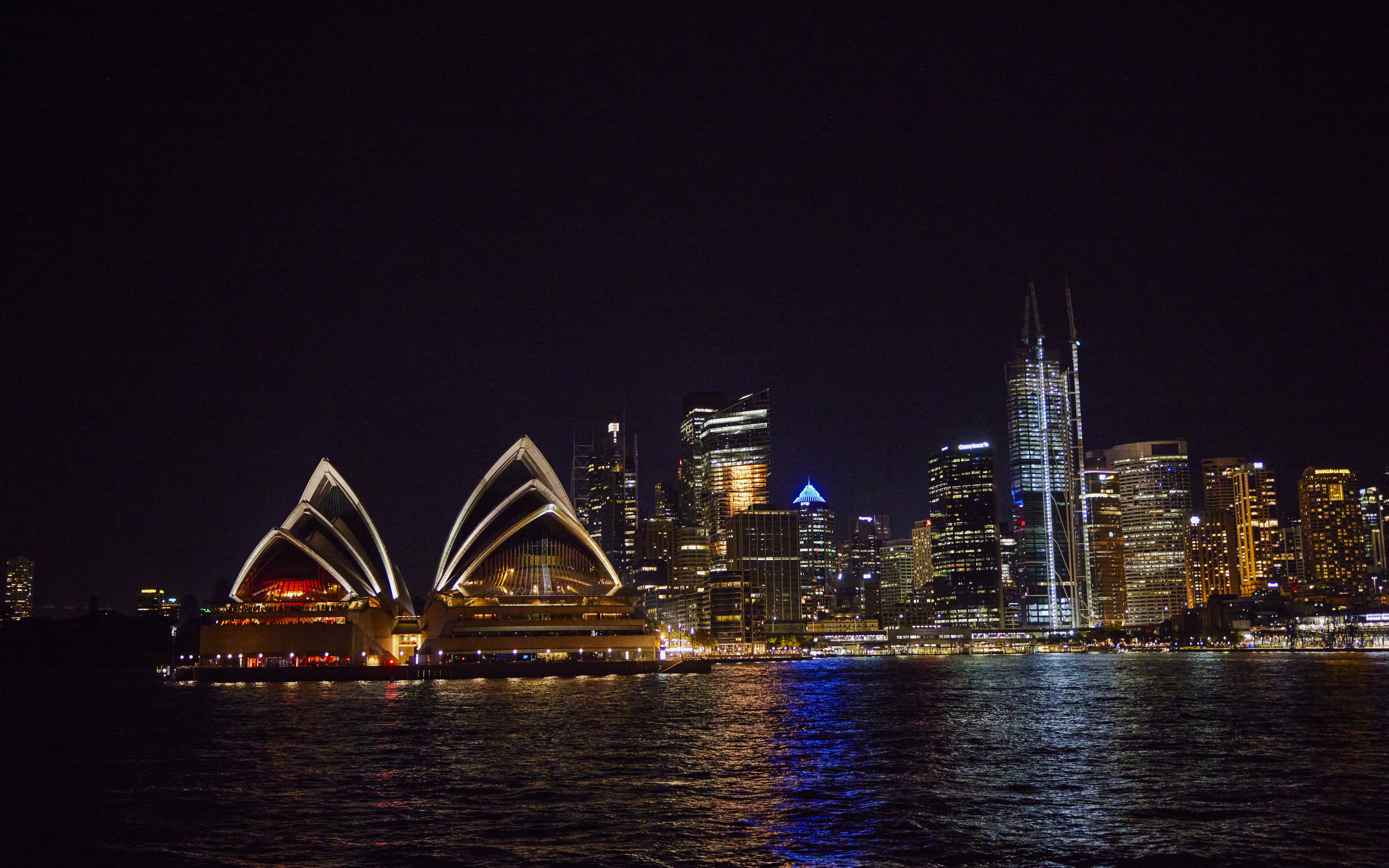 Sydney Opera House and city skyline at night during Vivid Sydney dinner cruise.
