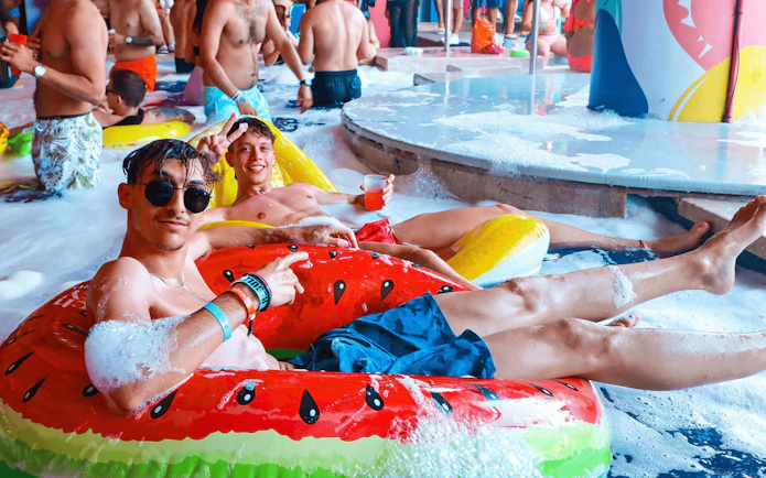 Guests enjoying foam party at Coco Bongo Beach Party in inflatable tubes.