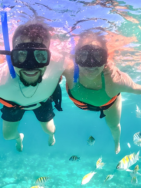 Snorkelers exploring vibrant fish in clear tropical waters.