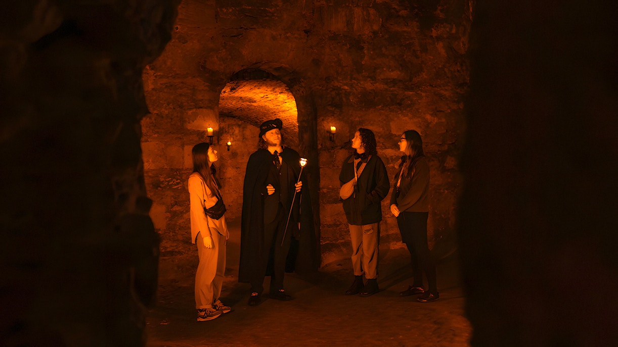 Tour guide leading a group in Edinburgh underground vaults on the Doomed, Dead and Buried Tour.