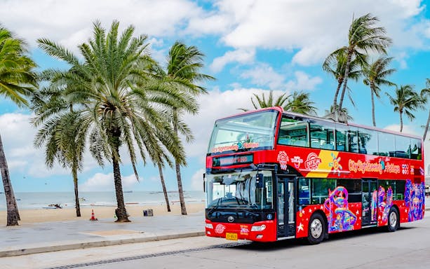 Pattaya Hop-On Hop-Off bus by Elephant Bus Tours with palm trees and beach in the background.