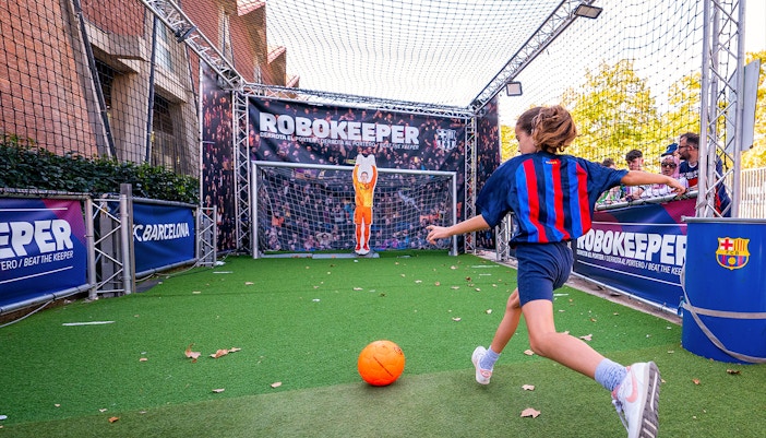 Child interacting with RoboKeeper exhibit at Camp Nou Barça Museum, Barcelona.