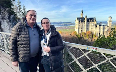 Visitors on a bridge with Neuschwanstein Castle in the background, Bavaria, Germany.