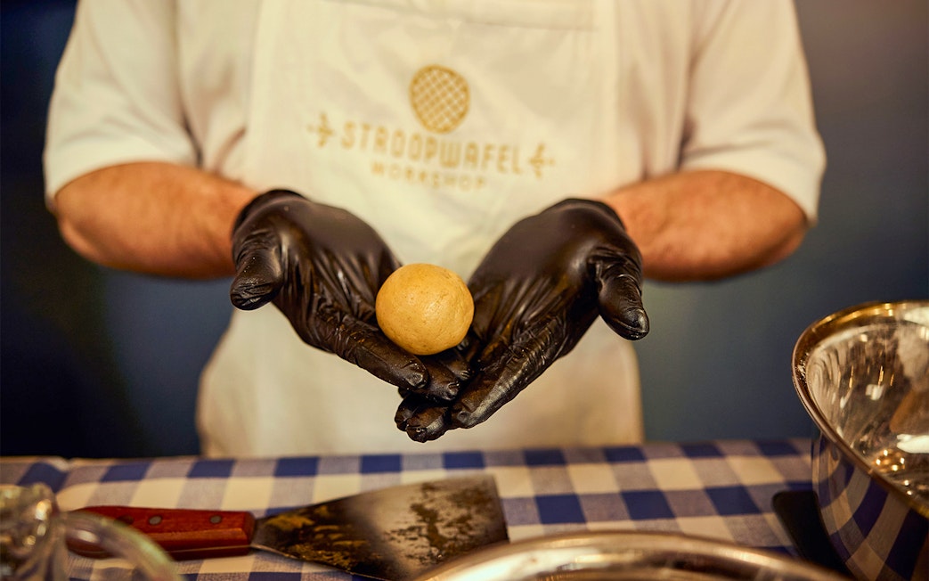 Hands shaping dough at Dutch waffle making workshop.