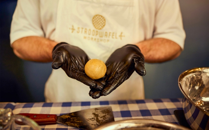 Hands shaping dough at Dutch waffle making workshop.