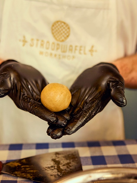 Hands shaping dough at Dutch waffle making workshop.