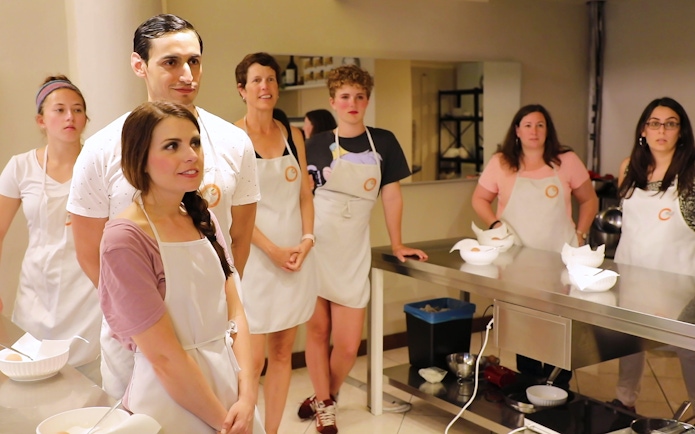 Participants in a cooking class at Florence Central Market, wearing aprons and listening attentively.