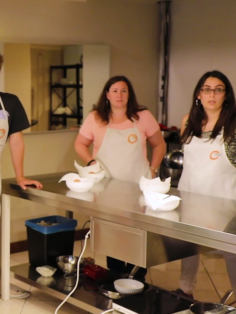 Participants in a cooking class at Florence Central Market, wearing aprons and listening attentively.