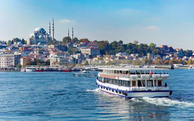 Bosphorus cruise ship sailing with Istanbul skyline and mosque in the background.