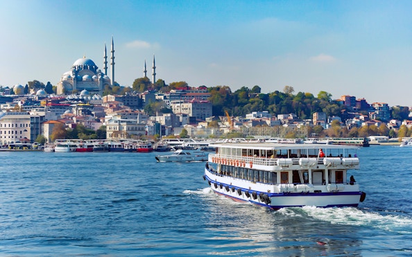 Bosphorus cruise ship sailing with Istanbul skyline and mosque in the background.