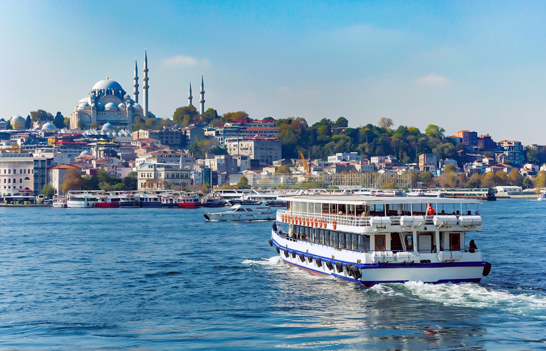 Bosphorus cruise ship sailing with Istanbul skyline and mosque in the background.
