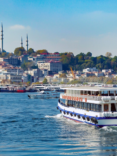 Bosphorus cruise ship sailing with Istanbul skyline and mosque in the background.