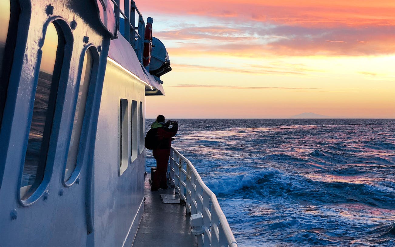 Visitor on a boat watching the ocean during Reykjavik Classic Whales in the Midnight Sun tour.