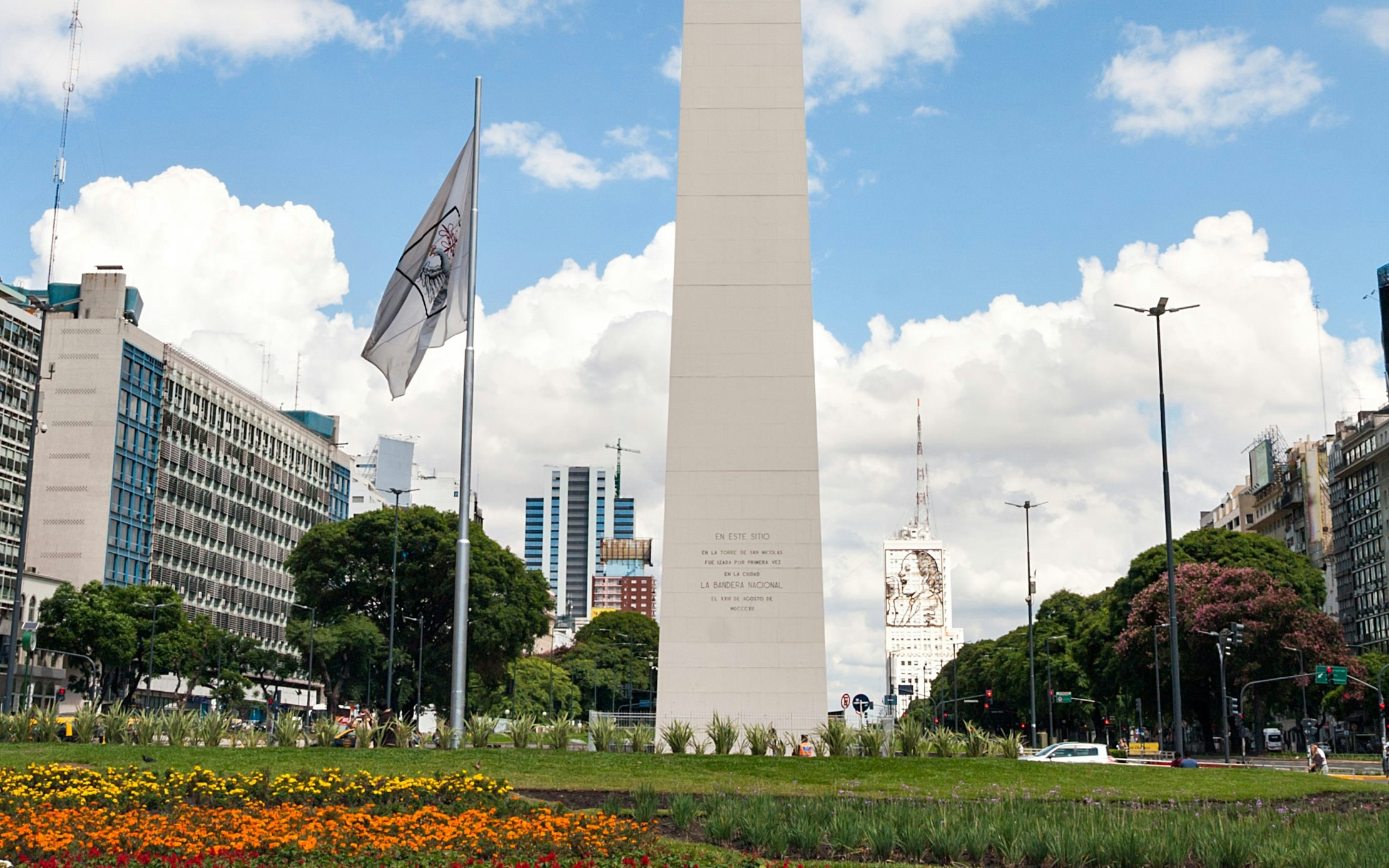 Obelisco in Buenos Aires with surrounding cityscape and colorful flowers in the foreground.