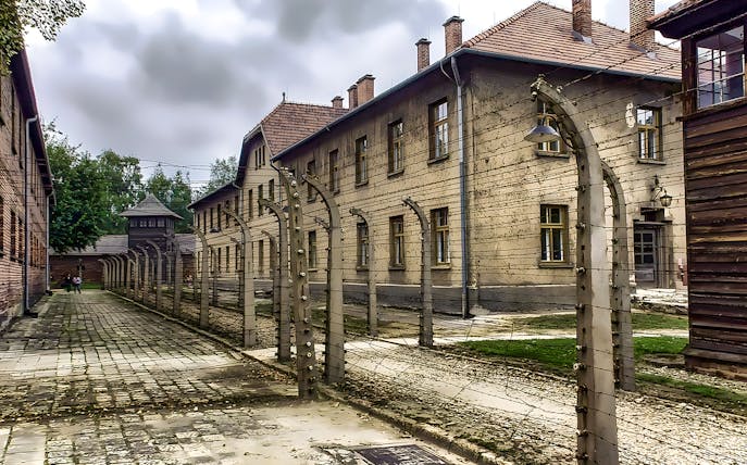 Auschwitz-Birkenau concentration camp buildings and barbed wire fence on a guided tour.