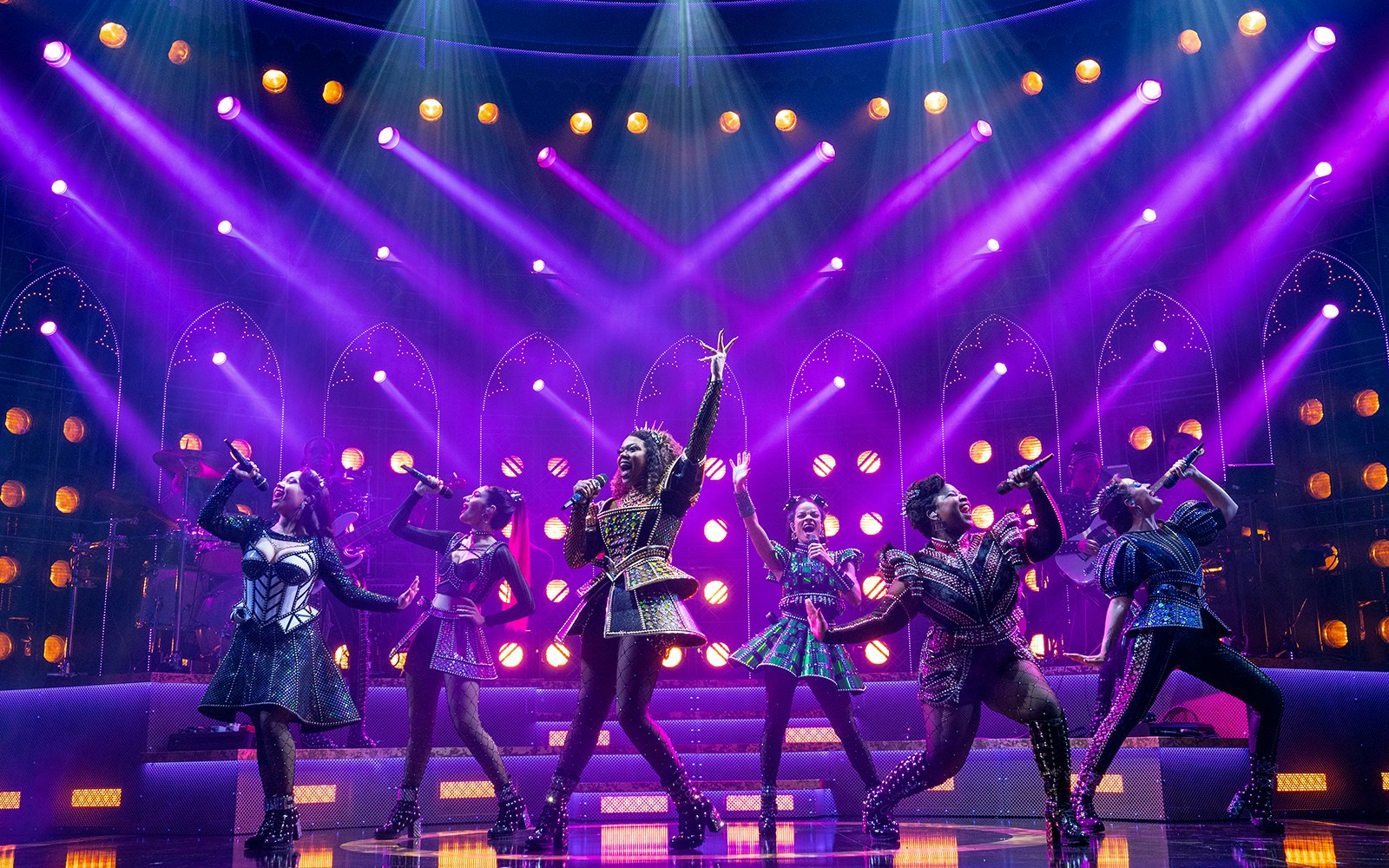 Performers on stage during SIX: The Musical with vibrant lighting.