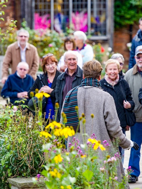 Group enjoying a guided tour in a garden setting.