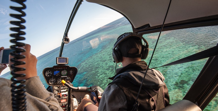 Helicopter flying over the Great Barrier Reef, showcasing coral formations, Australia.