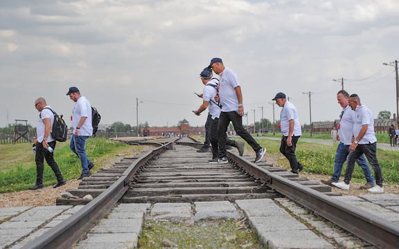 Group of tourists crossing the railway track at Auschwitz-Birkenau concentration camp