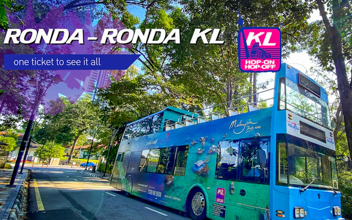 KL Hop-on Hop-off bus on a tree-lined street, promoting city sightseeing and Aquaria KLCC tour.