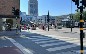 Pedestrians crossing a street in Södermalm, Stockholm, with modern buildings in the background.