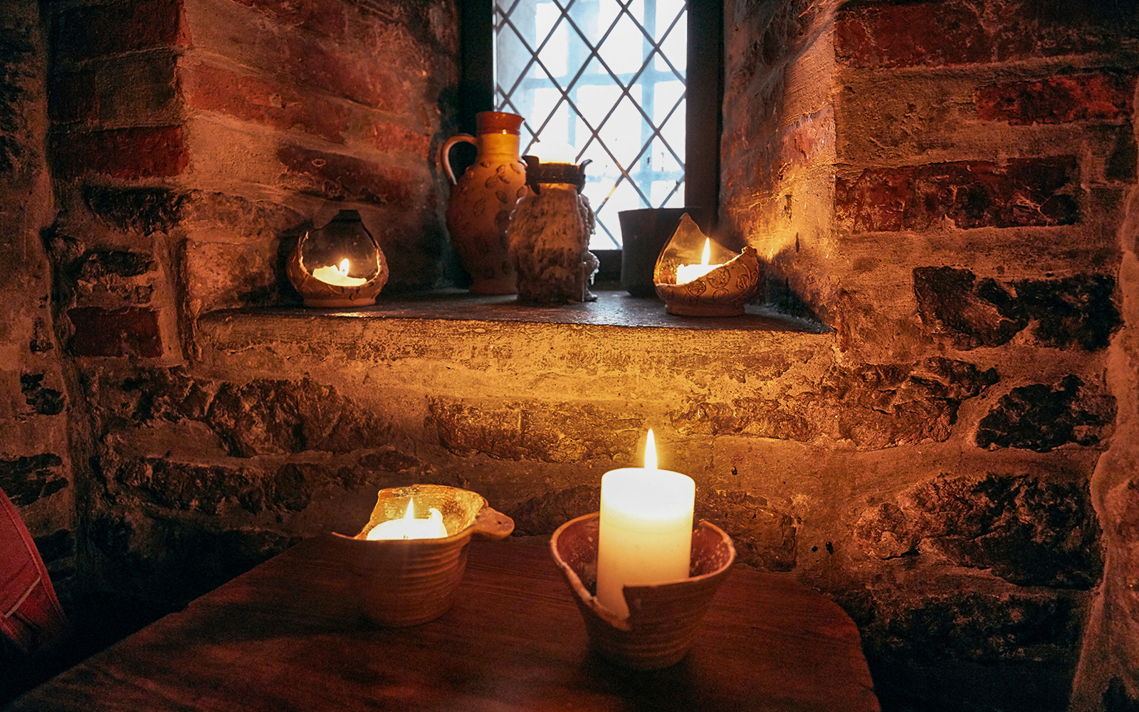 Candlelit medieval setting in Prague with rustic pottery and stone walls.