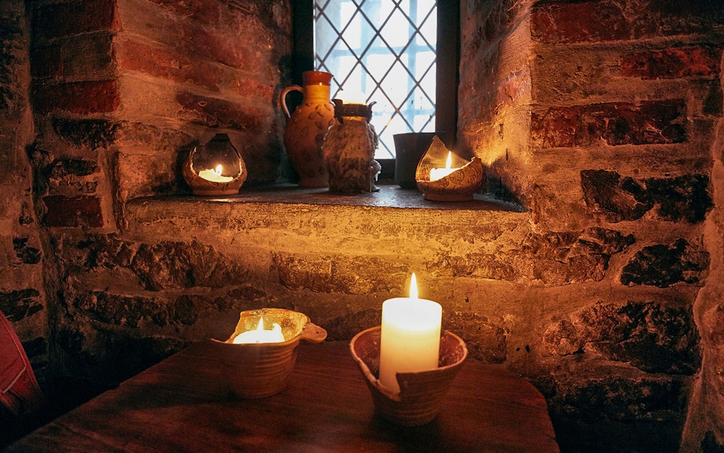 Candlelit medieval setting in Prague with rustic pottery and stone walls.