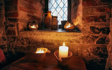 Candlelit medieval setting in Prague with rustic pottery and stone walls.