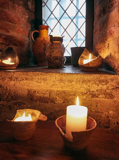 Candlelit medieval setting in Prague with rustic pottery and stone walls.