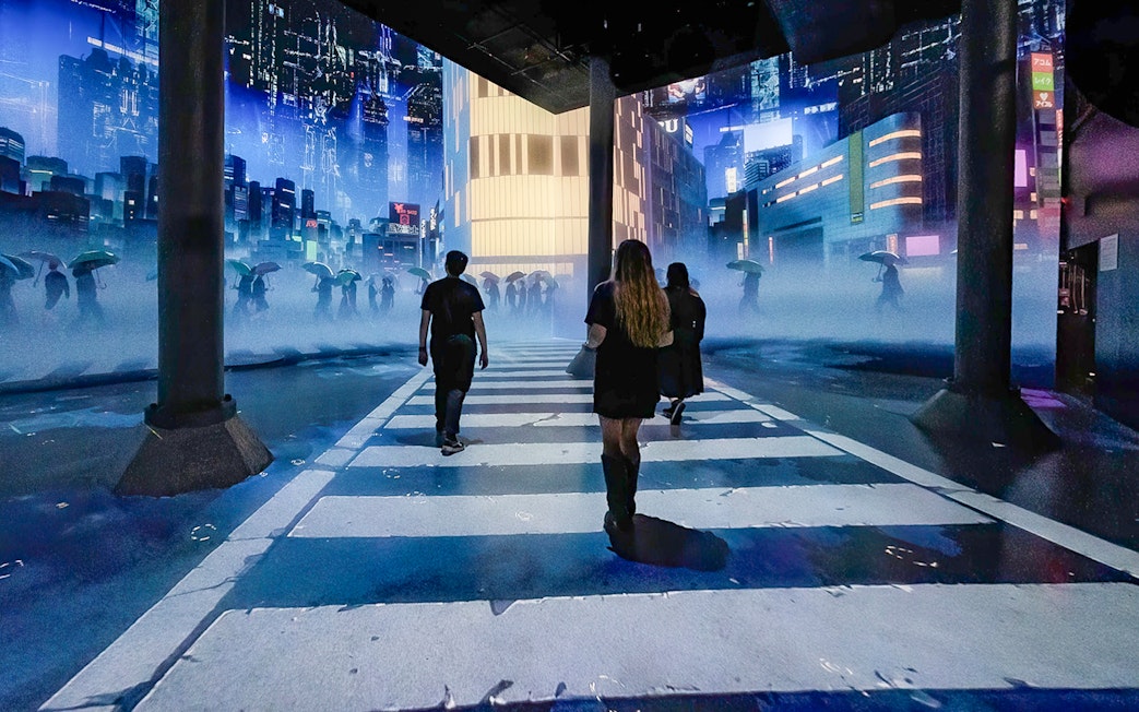 Guests walking through digital cityscape exhibit at ARTECHOUSE New York.