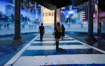 Guests walking through digital cityscape exhibit at ARTECHOUSE New York.