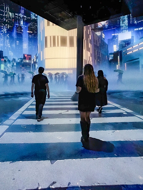 Guests walking through digital cityscape exhibit at ARTECHOUSE New York.