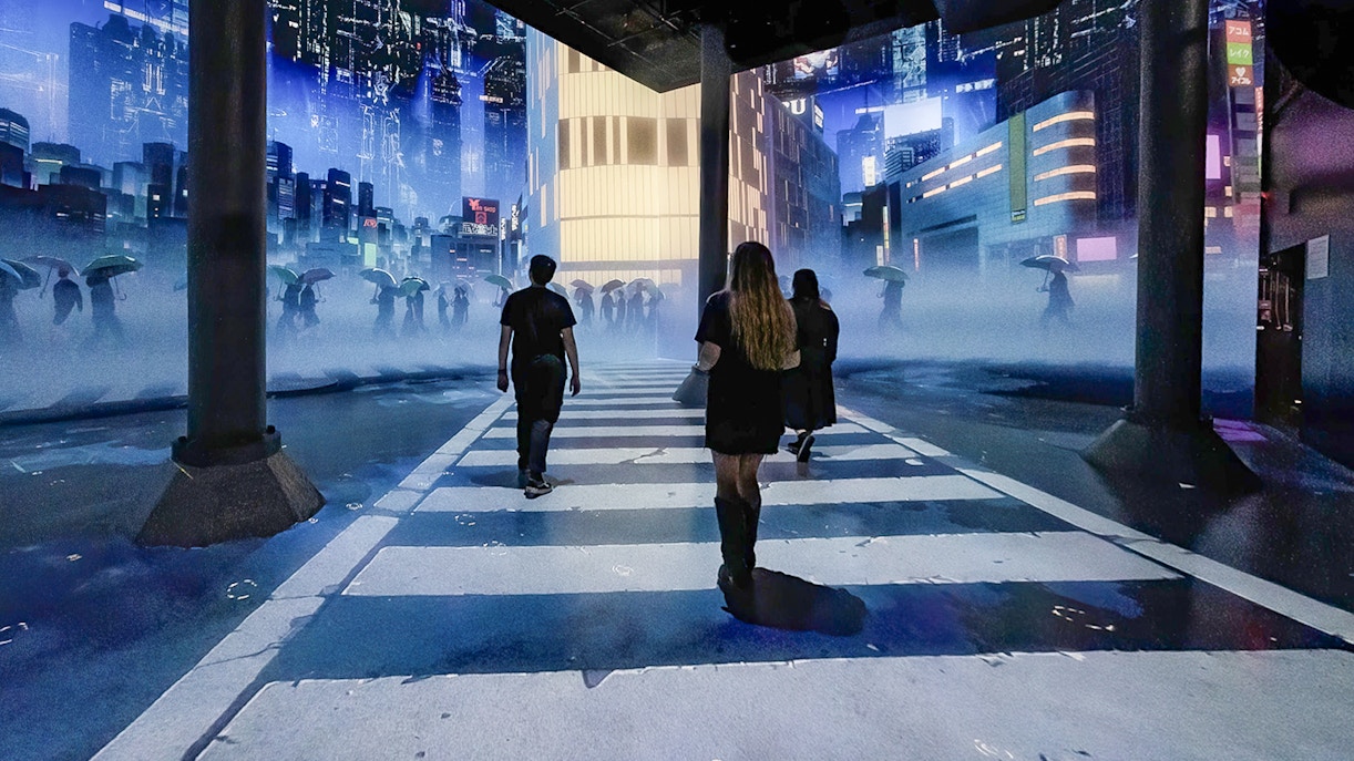 Guests walking through digital cityscape exhibit at ARTECHOUSE New York.