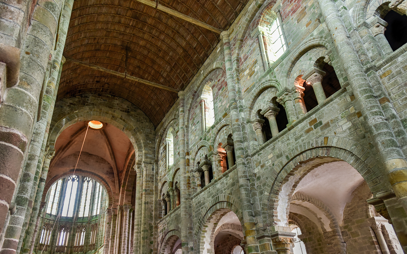 Interior of Mont Saint-Michel Abbey with stone arches and vaulted ceiling.
