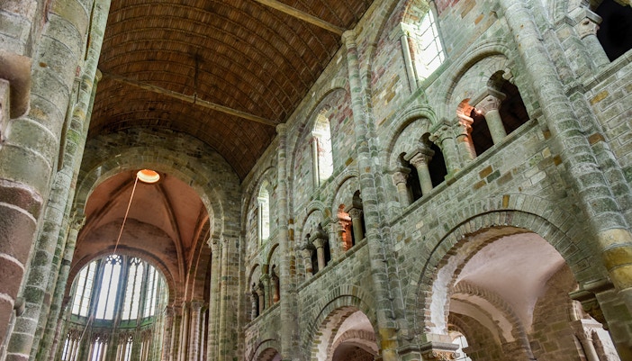 Interior of Mont Saint-Michel Abbey with stone arches and vaulted ceiling.