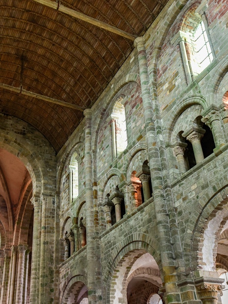 Interior of Mont Saint-Michel Abbey with stone arches and vaulted ceiling.