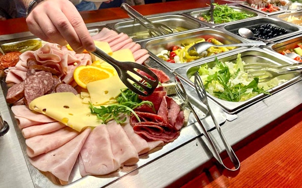 Assorted meats and cheeses on a buffet during Prague sightseeing boat cruise.