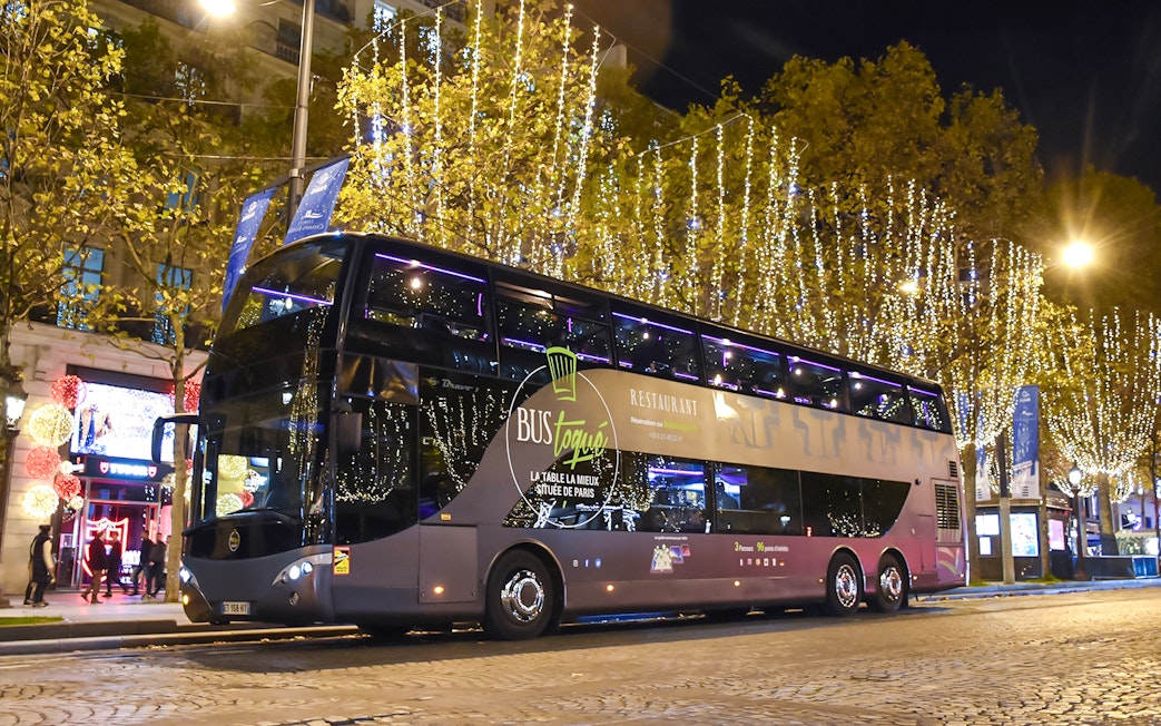 Bus Toqué Paris at night with festive lights on the Champs-Élysées.
