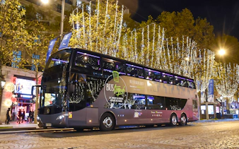 Bus Toqué Paris at night with festive lights on the Champs-Élysées.