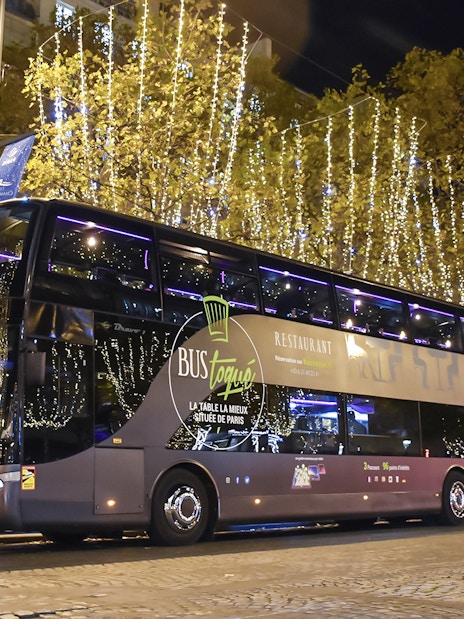Bus Toqué Paris at night with festive lights on the Champs-Élysées.