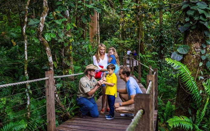 Family interacting with guide on rainforest boardwalk at Barron Falls Skyrail Station.