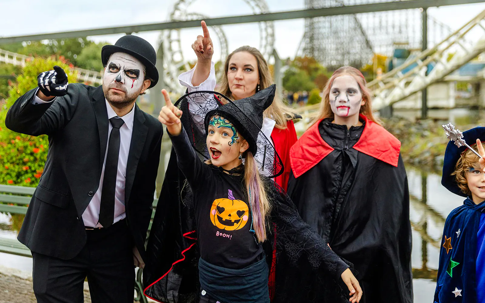 Group in Halloween costumes pointing at Heide Park attractions.
