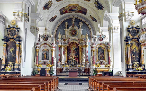 Interior of Engelberg Abbey church with ornate altar and frescoes, part of Lucerne tour.