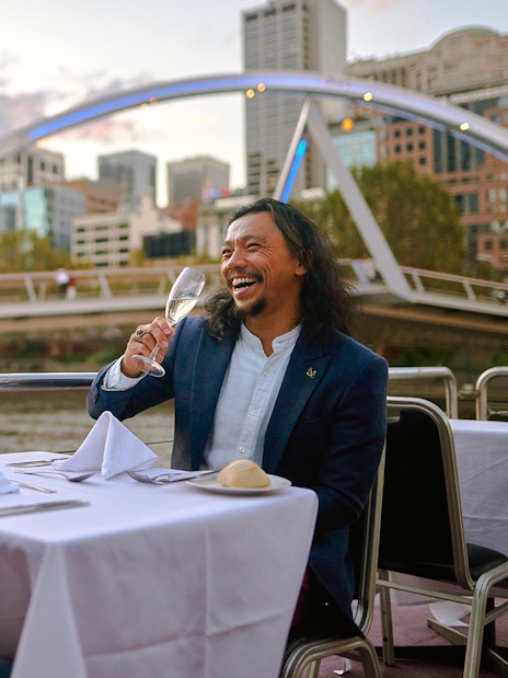 Couple enjoying wine on the Spirit of Melbourne Dinner Cruise with city skyline in the background.