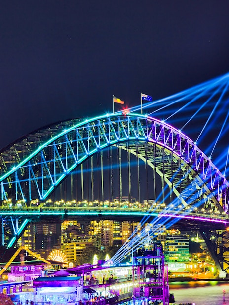 Sydney Harbour Bridge illuminated during Vivid Sydney, viewed from a tall ship dinner cruise.