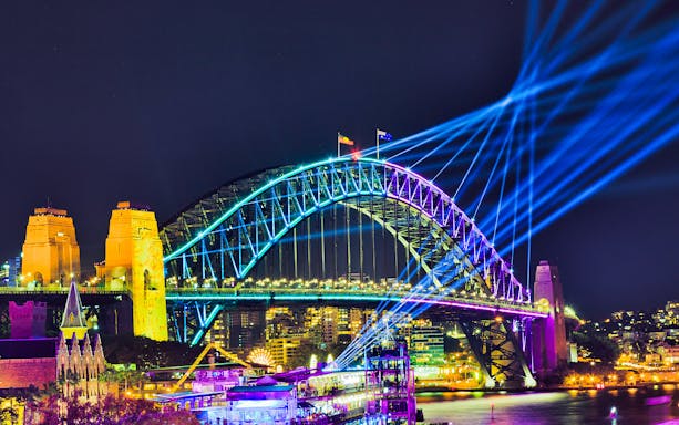 Sydney Harbour Bridge illuminated during Vivid Sydney, viewed from a tall ship dinner cruise.