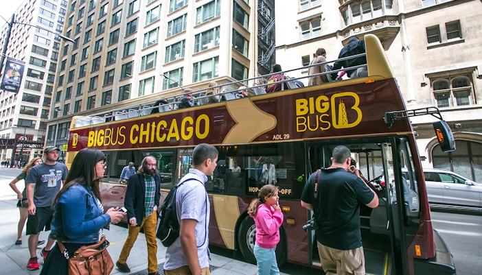 Double-decker bus on Chicago Hop-On-Hop-Off Tour passing by the iconic Chicago skyline.